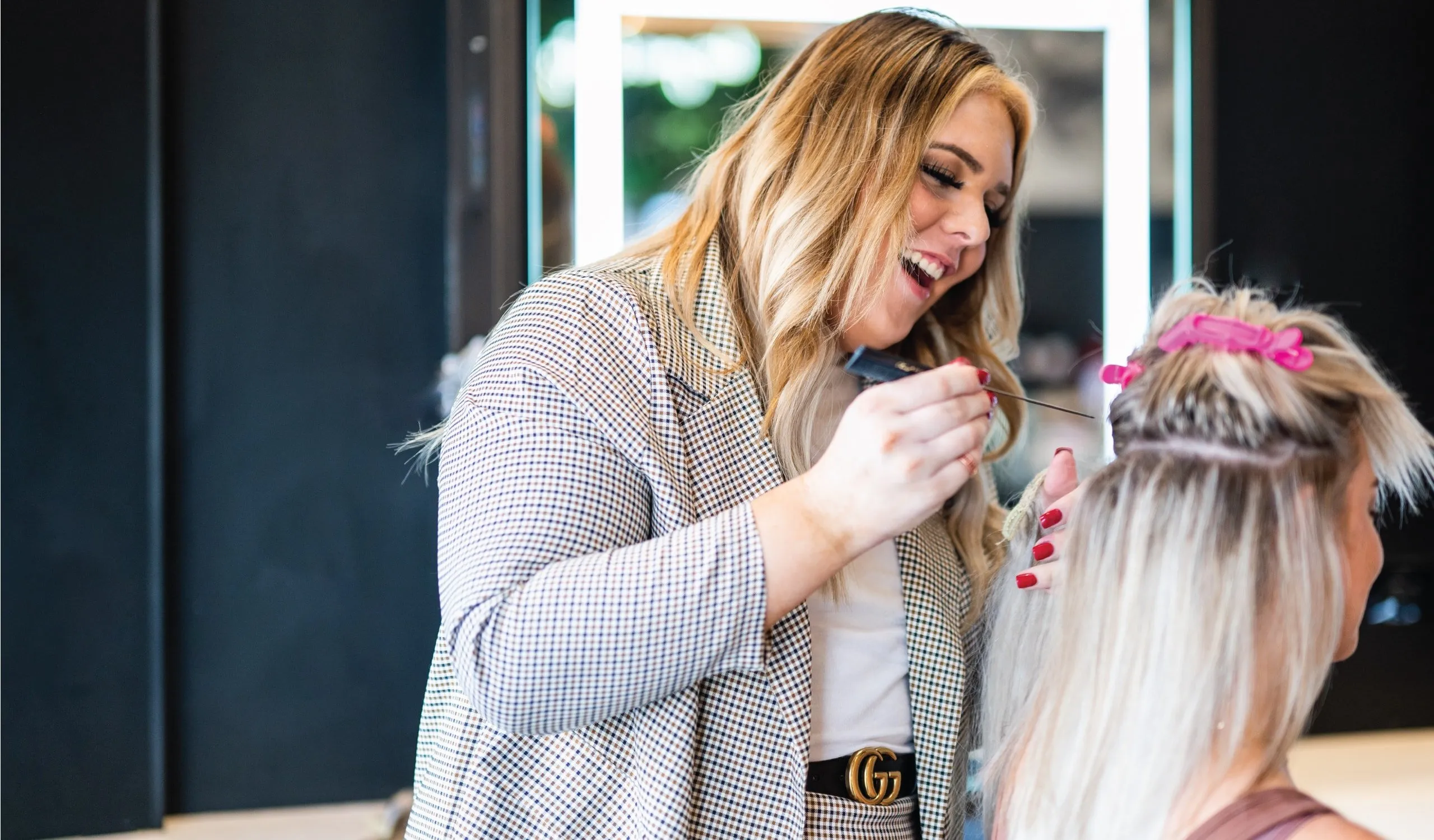 Stylist fitting blonde hair extensions for a salon client